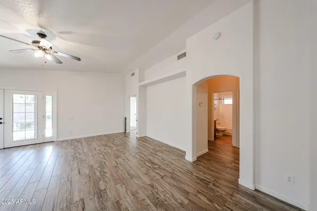 a view of an empty room with window and wooden floor
