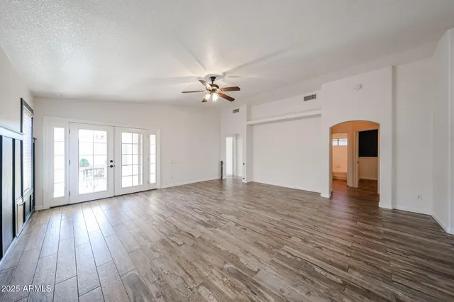 a view of empty room with wooden floor and ceiling fan
