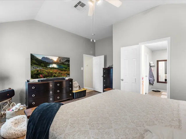 a bedroom with a bed and a flat tv screen on dresser
