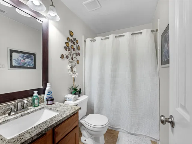 a bathroom with a granite countertop sink toilet and a mirror