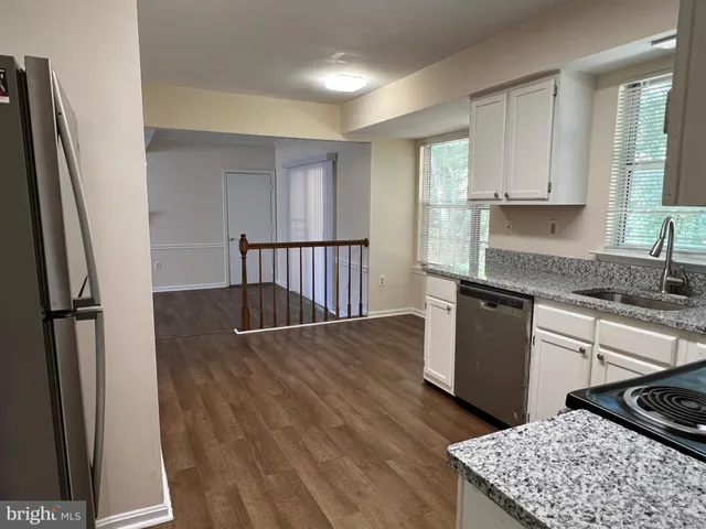 a kitchen with stainless steel appliances granite countertop a refrigerator a stove and a sink with wooden floor