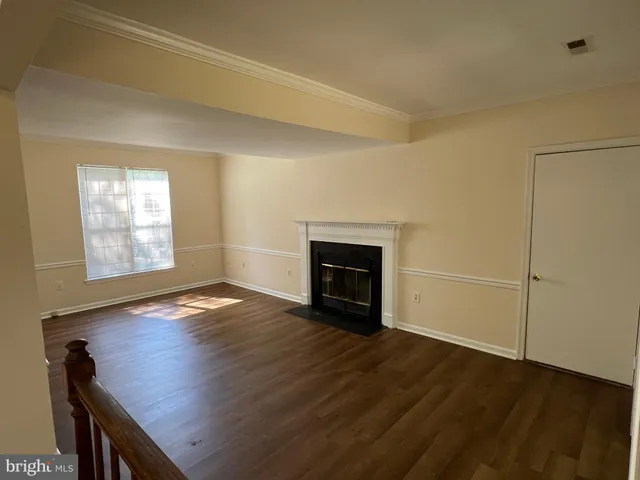 an empty room with wooden floor fireplace and windows