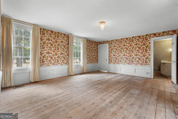a view of an empty room with a window and wooden floor