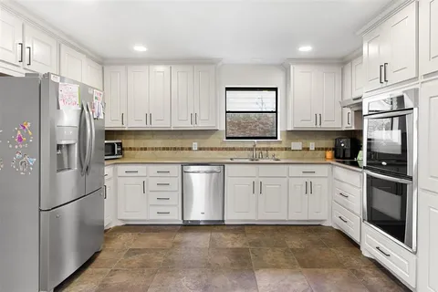 a kitchen with granite countertop white cabinets and stainless steel appliances