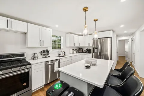a kitchen with a sink a stove a refrigerator and white cabinets