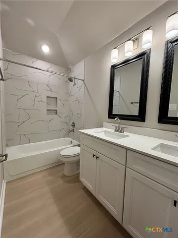 a bathroom with a double vanity sink toilet mirror and bathtub
