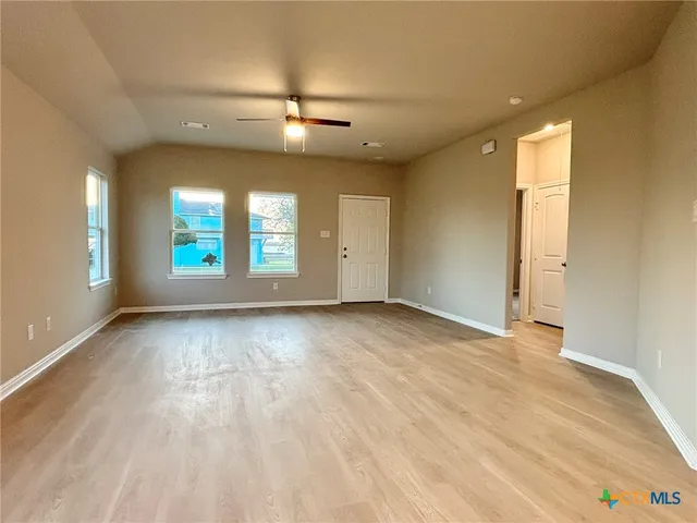 an empty room with wooden floor and windows