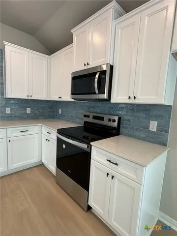 a kitchen with white cabinets and white appliances