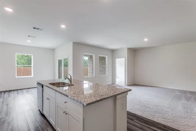 a kitchen with granite countertop a sink and dishwasher with wooden floor