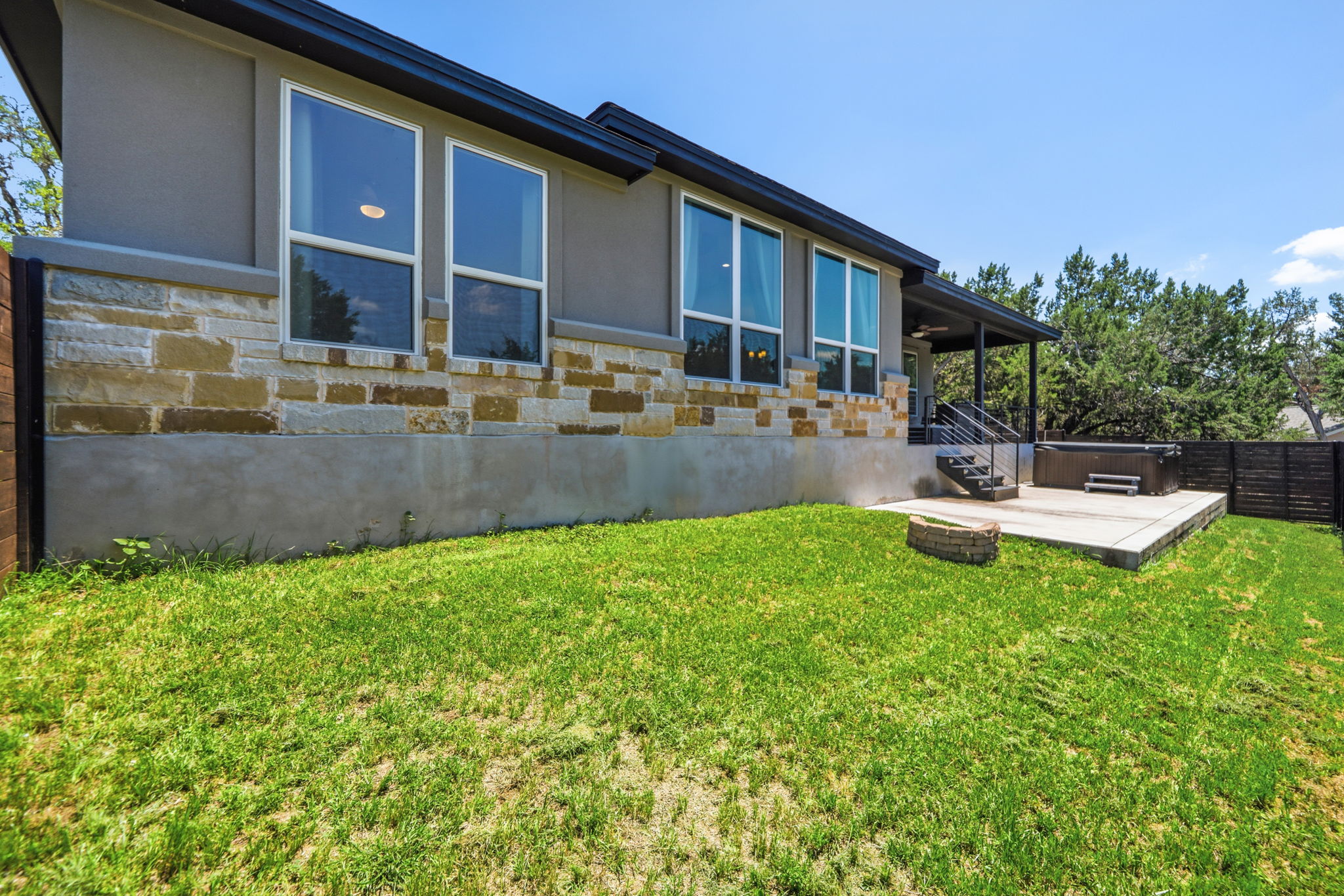 18605 Masters Cove Point Venture, TX 78645 - Photo 31 of 40 Exterior featuring stone and stucco siding, a covered patio, and a dedicated concrete pad with a built-in spa
