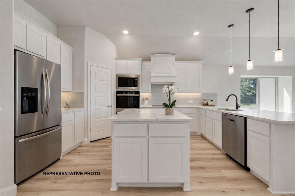 1005 Monaco Court Springtown, TX 76082 - Photo 5 of 12 a kitchen with kitchen island white cabinets and stainless steel appliances