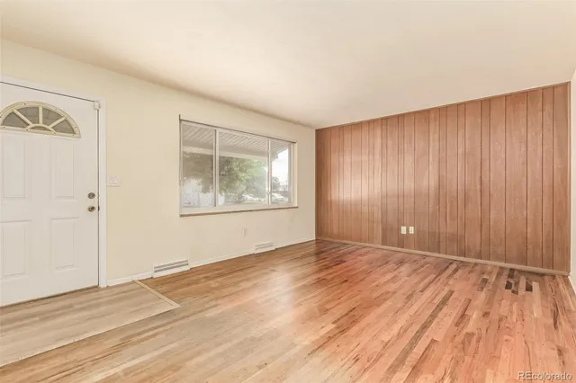 a view of an empty room with wooden floor and a window