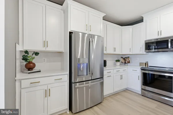 a kitchen with stainless steel appliances white cabinets white stove a refrigerator and a sink with wooden floor