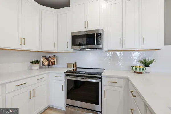 a kitchen with stainless steel appliances granite countertop white cabinets a stove top oven a sink and dishwasher