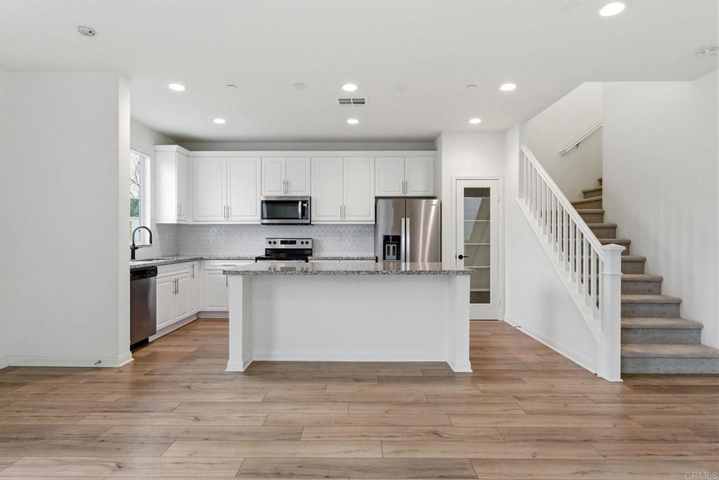 2711 Jujube Street Spring Valley, CA 91977 - Photo 9 of 31 a view of kitchen with microwave stove refrigerator and white cabinets with wooden floor