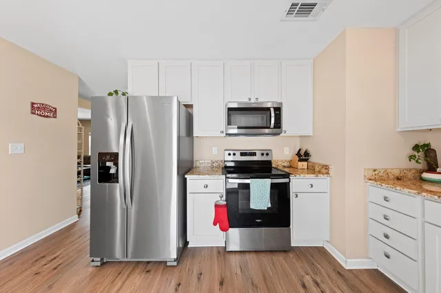 a kitchen with a refrigerator a stove top oven a sink and dishwasher with wooden floor