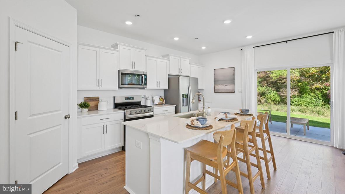 410 Scotty Boulevard, Unit 1006 Rio Grande, NJ 08242 - Photo 17 of 57 a kitchen with stainless steel appliances granite countertop a stove top oven a sink dishwasher a dining table and chairs with wooden floor