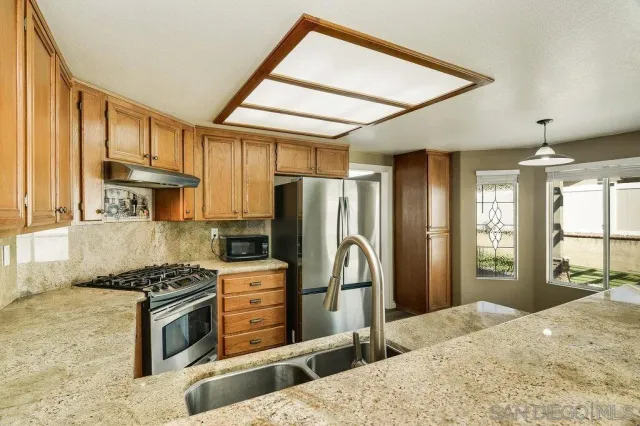 a kitchen with stainless steel appliances kitchen island granite countertop a refrigerator and a stove top oven