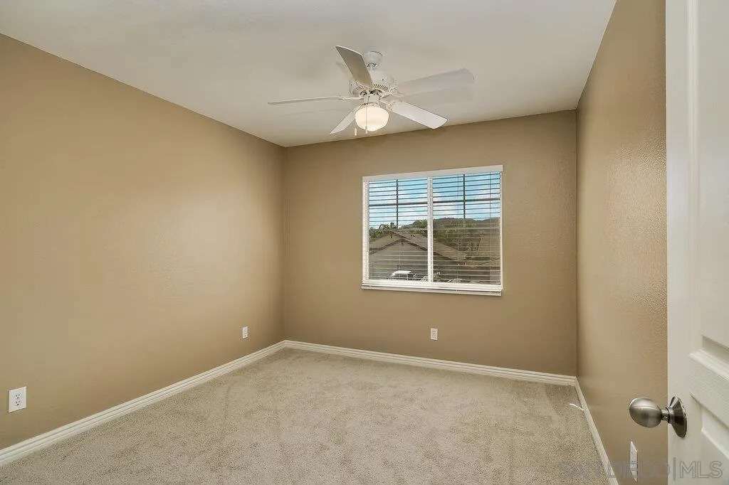 11212 Callio Way Lakeside, CA 92040 - Photo 27 of 50 an empty room with a chandelier fan and windows