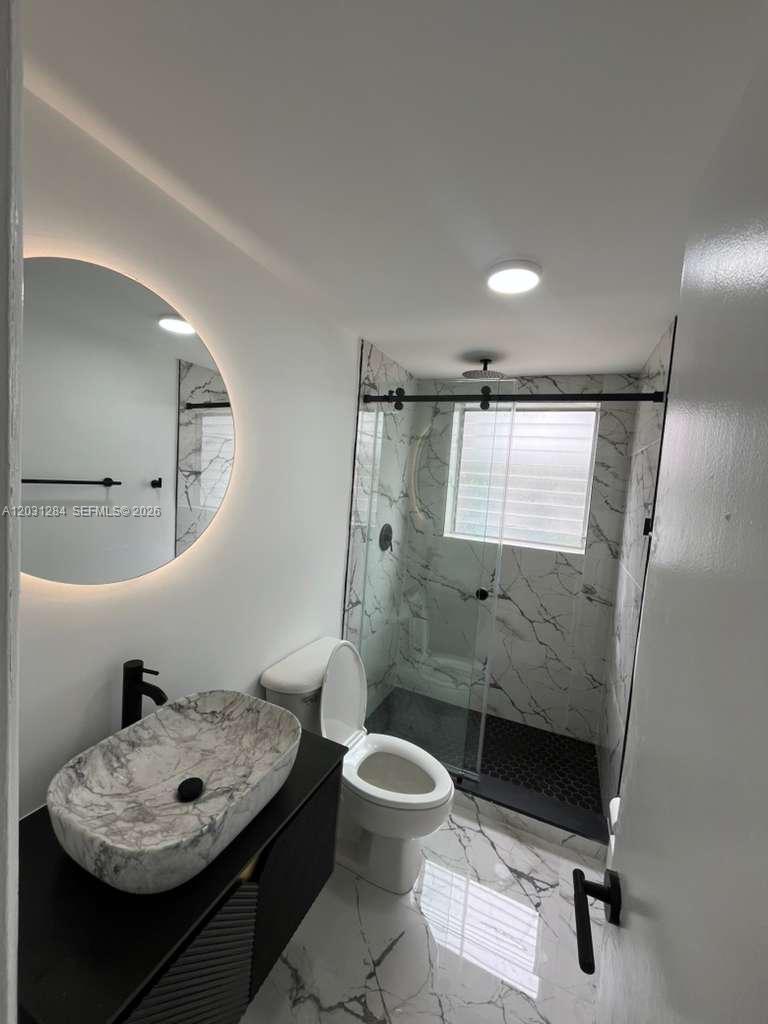 316 Surfside Boulevard, Unit 2 Surfside, FL 33154 - Photo 1 of 13 a bathroom with a toilet a sink and mirror