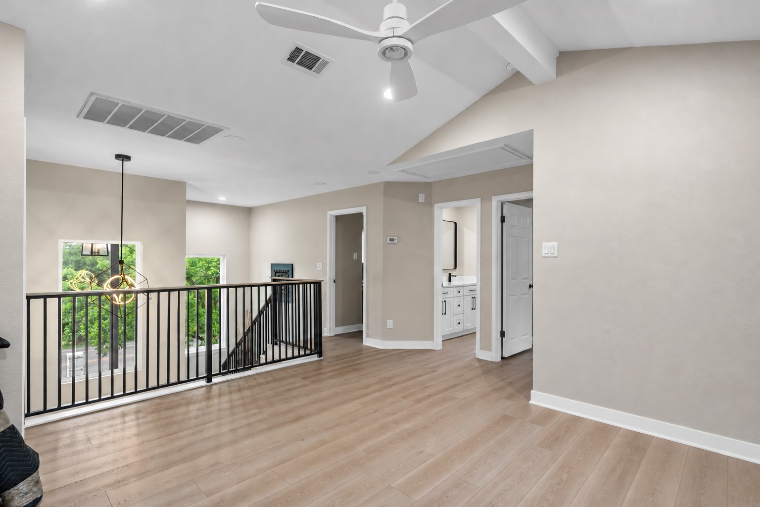 307 Hurst Creek Road Austin, TX 78734 - Photo 22 of 40 Spacious upper-level landing featuring vaulted ceilings, wood-finish flooring, a contemporary ceiling fan, and a black metal railing overlooking a lower space