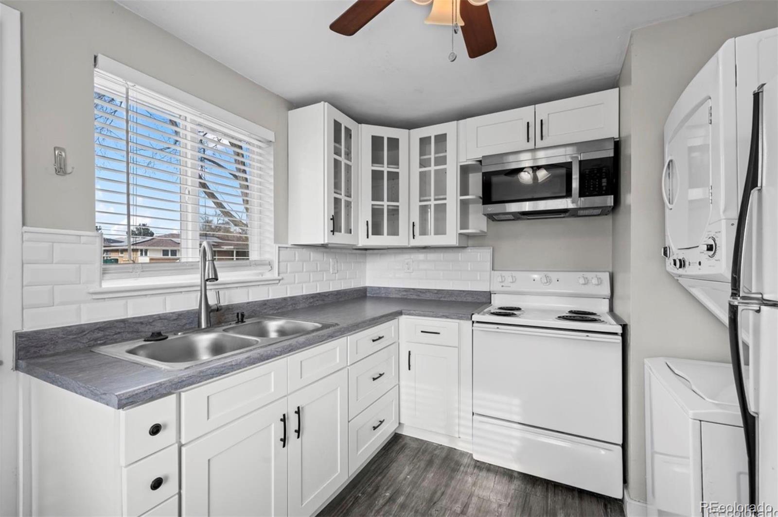 8795 West 46th Avenue Wheat Ridge, CO 80033 - Photo 5 of 12 a kitchen with stainless steel appliances granite countertop a sink a stove and microwave