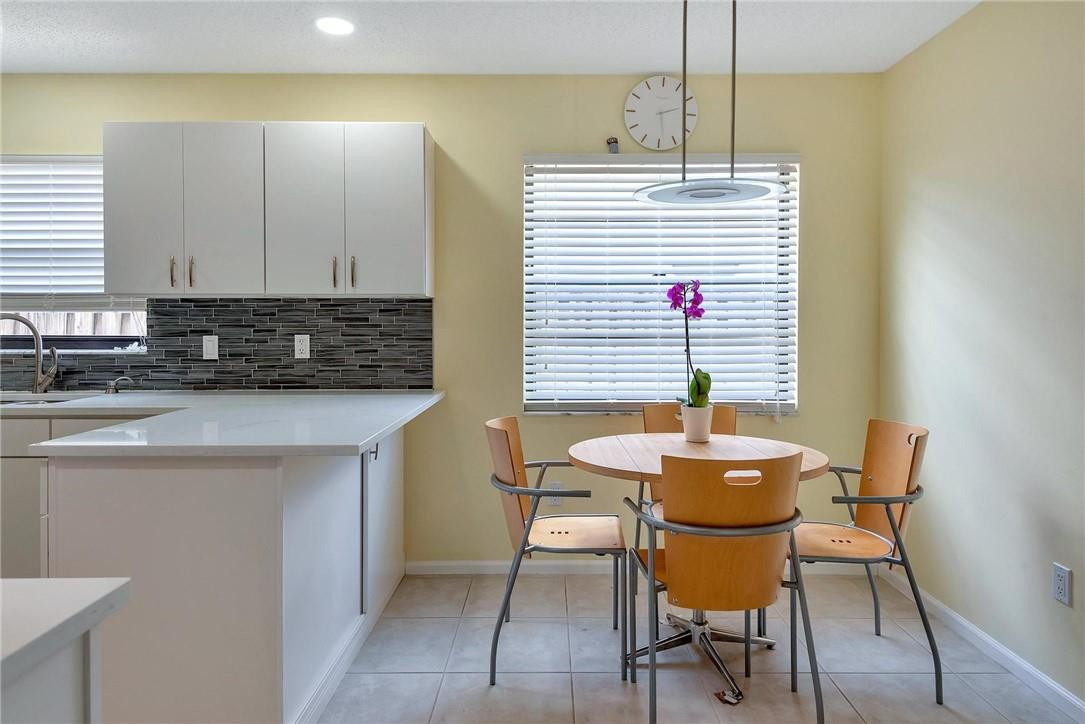 23090 Southwest 56th Avenue Boca Raton, FL 33433 - Photo 11 of 49 a kitchen with a dining table chairs and white cabinets