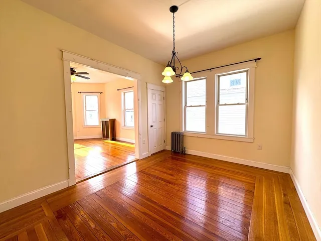 a view of an empty room with window and wooden floor