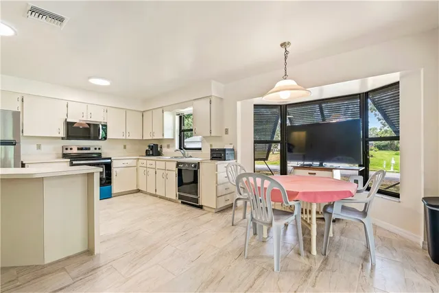 a kitchen with a dining table chairs refrigerator and microwave