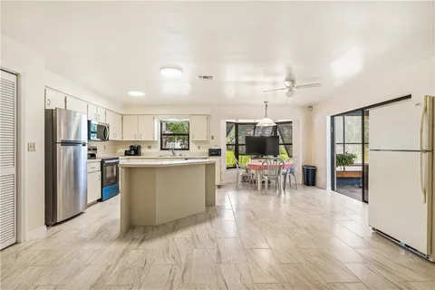 a view of a kitchen with dining area a sink a refrigerator and window