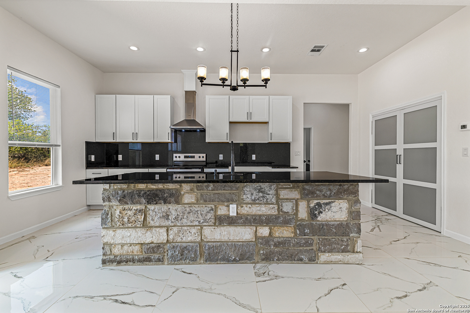 120 County Road 6852 Lytle, TX 78052 - Photo 14 of 36 a kitchen with kitchen island granite countertop a stove a sink a window and white cabinets