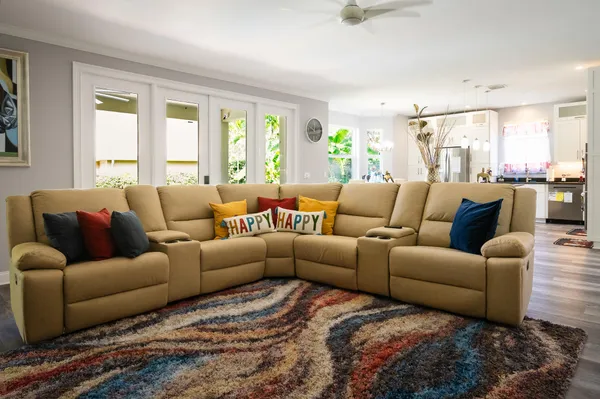 a living room with furniture kitchen view and a wooden floor