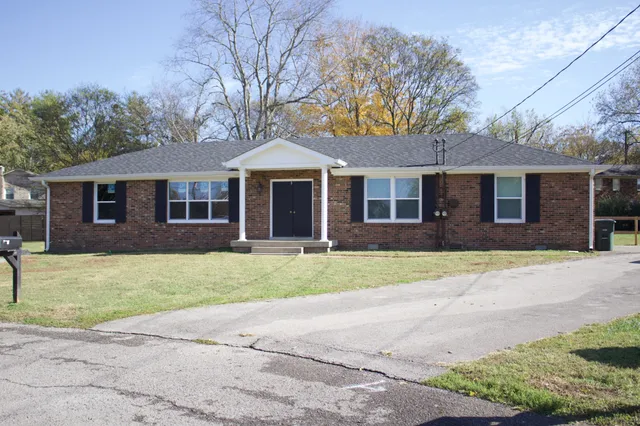 a front view of a house with a garden and trees