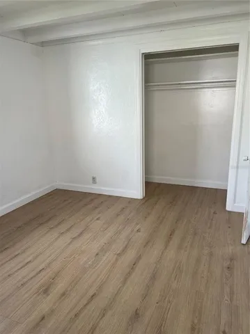 a view of an empty room with wooden floor and closet