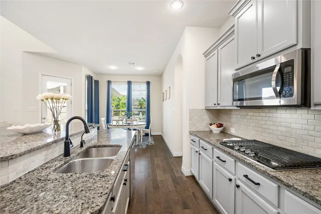 a kitchen with granite countertop a stove a sink and a microwave