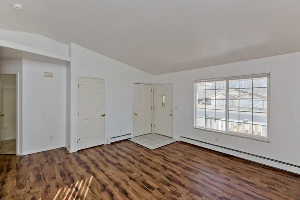 a view of an empty room with wooden floor and window