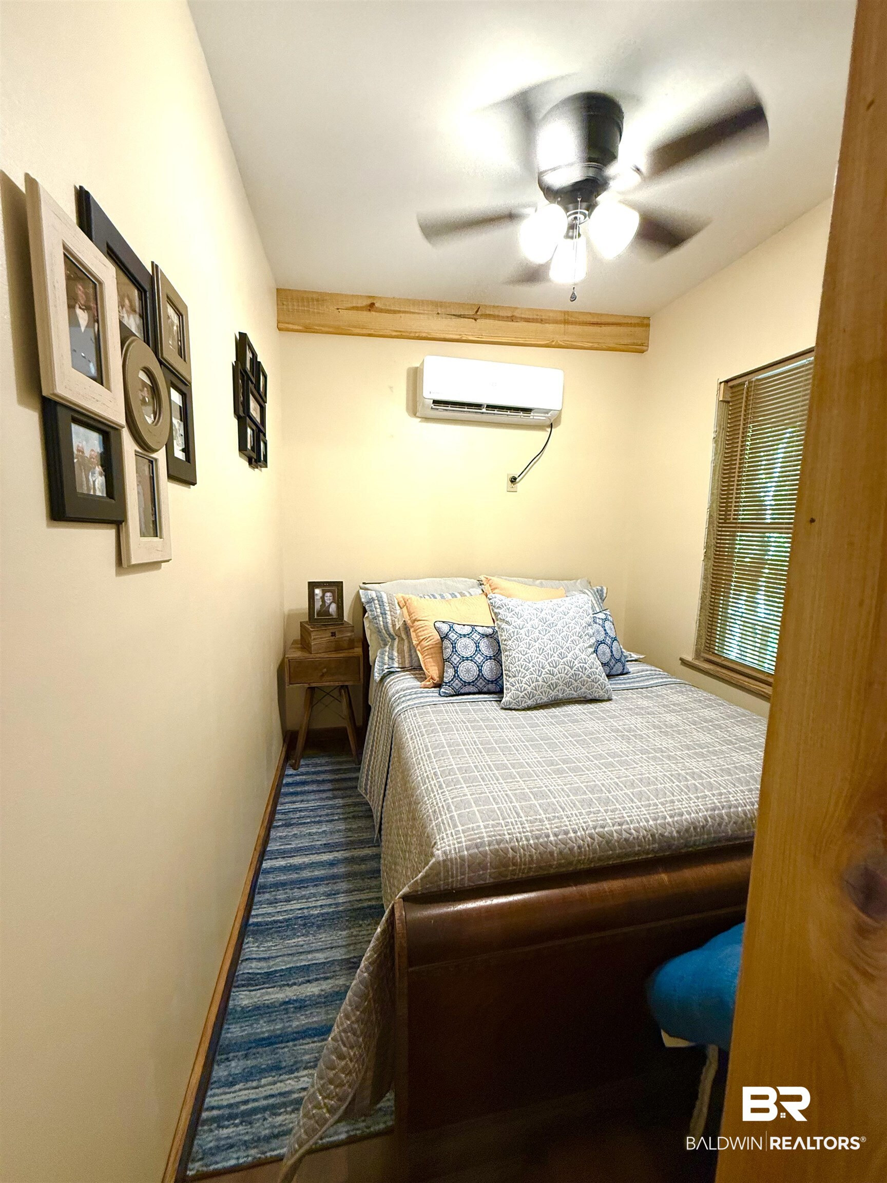 1 Mason Ferry Road Citronelle, AL 36522 - Photo 12 of 40 Compact sleeping area featuring wood-finish flooring, a wall-mounted mini-split system, a ceiling fan with integrated lighting, and a window with blinds