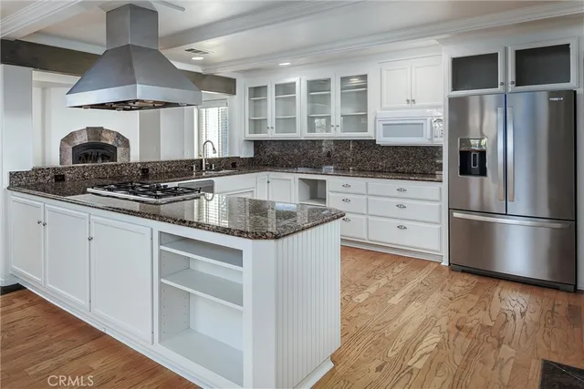a kitchen with stainless steel appliances granite countertop a stove a refrigerator and a sink with wooden floors