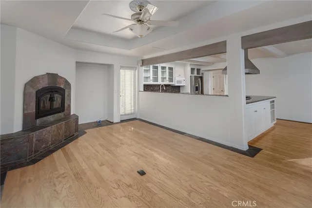 a view of empty room with wooden floor and kitchen view