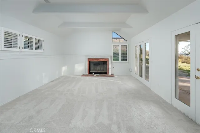 a view of empty room with floor to ceiling window and fireplace