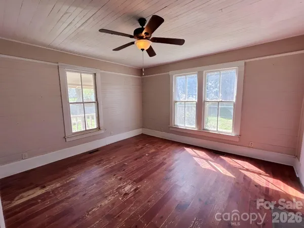 a view of empty room with wooden floor and fan