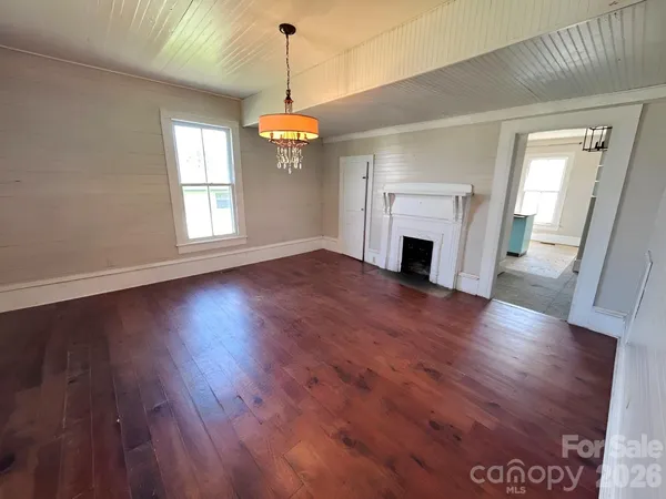 an empty room with wooden floor fireplace and windows