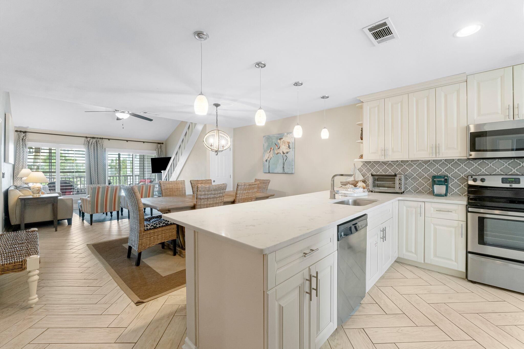 4984 West County Highway 30A Road, Unit 7B Santa Rosa Beach, FL 32459 - Photo 12 of 40 a large white kitchen with lots of counter space dining table and stainless steel appliances
