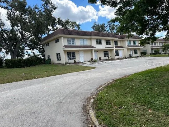 a view of a white house next to a yard with big trees