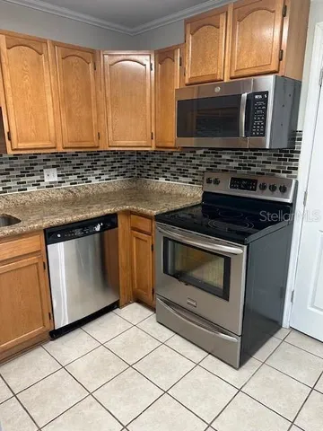 a kitchen with granite countertop a stove top oven microwave and cabinets