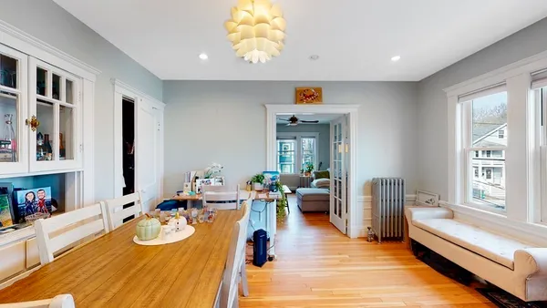 a dining room with wooden floor and large windows
