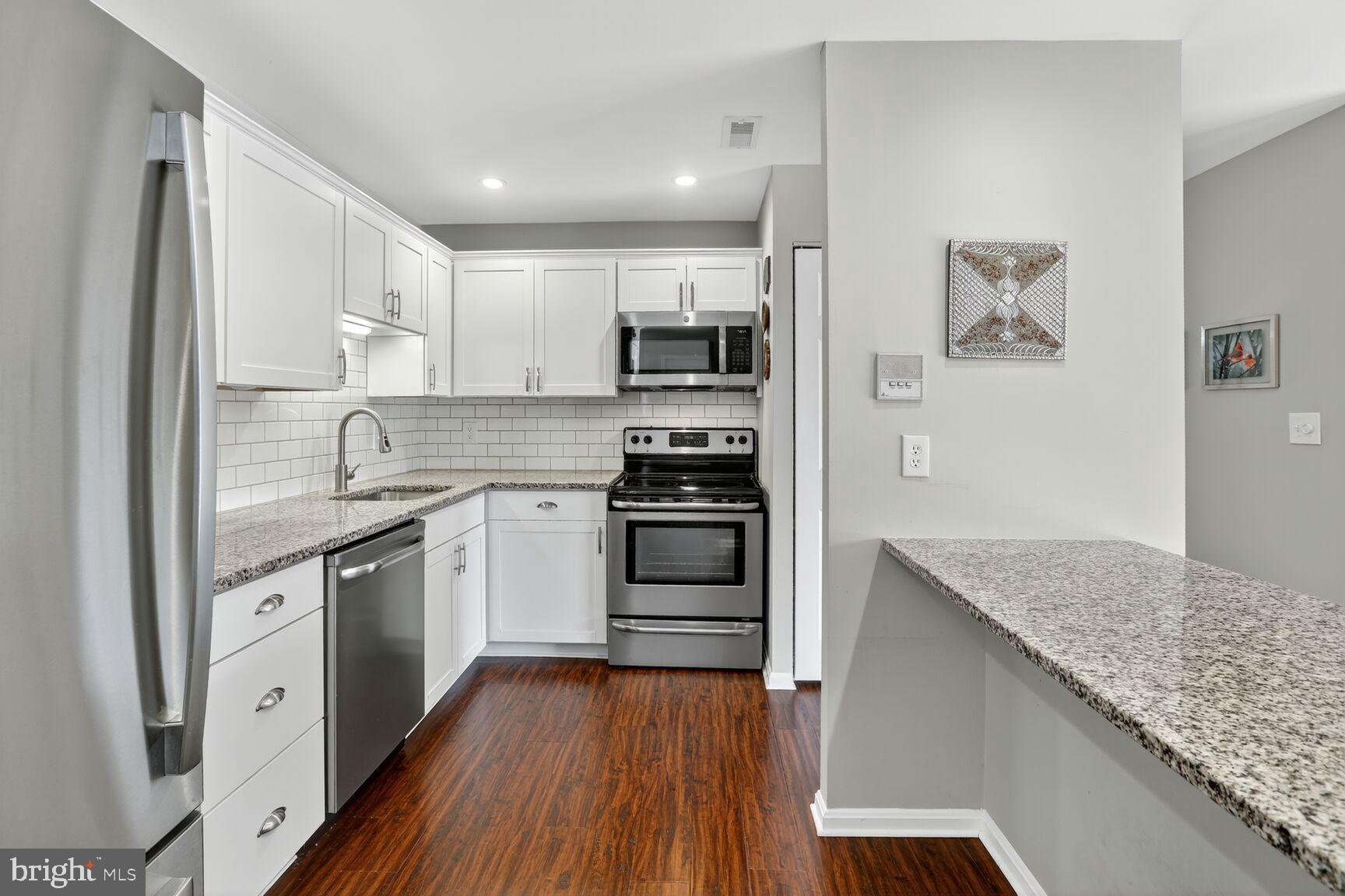 4106 Chardel Road, Unit 2G Baltimore, MD 21236 - Photo 10 of 25 a kitchen with stainless steel appliances granite countertop a stove top oven a sink and dishwasher with wooden floor