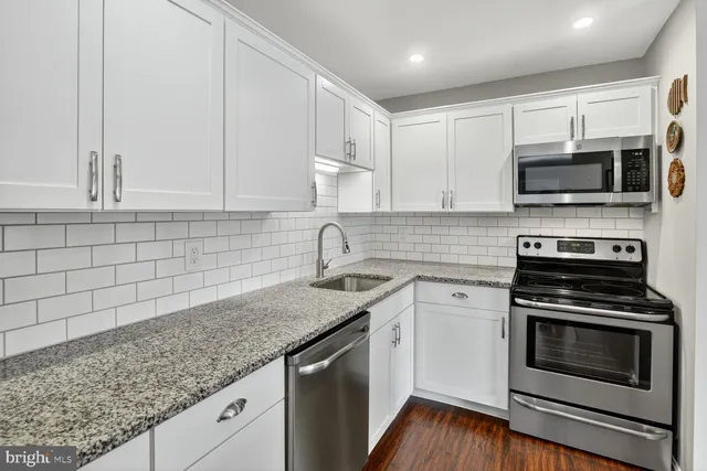 a kitchen with stainless steel appliances granite countertop a stove top oven a sink and dishwasher with wooden floor