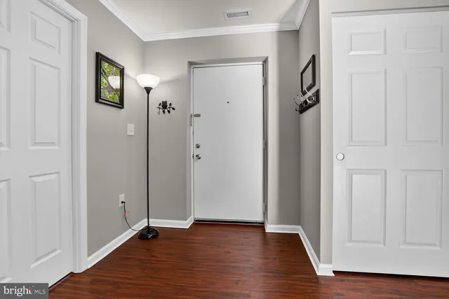 a view of an empty room with wooden floor and closet area