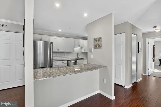 a view of a hallway with wooden floor and a kitchen